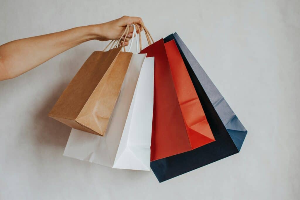 Hand holding colorful shopping bags against a light background