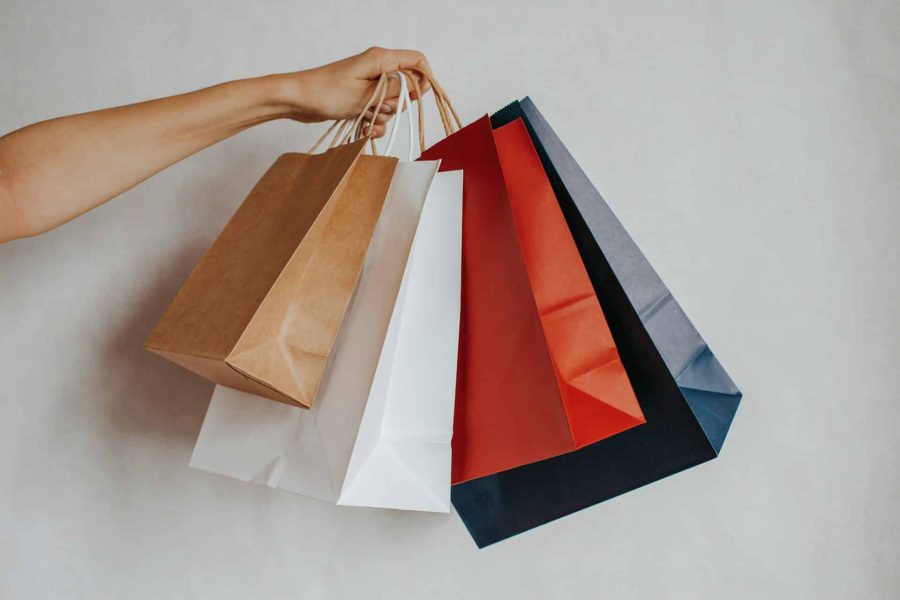 Hand holding colorful shopping bags against a light background