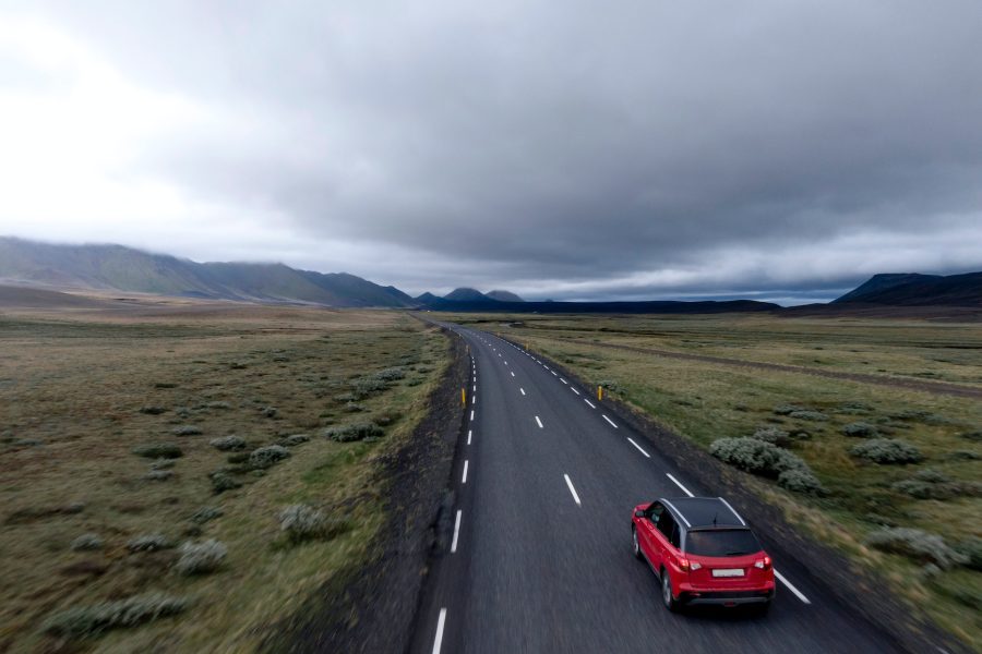 red hatchback vehicle on asphalt road
